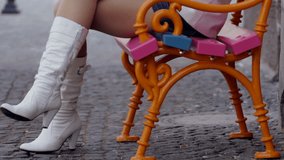 Close shot of a young woman reading a book on a colorful city bench. High definition video.