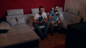 Two friends or brothers watching a match on television. High definition video.