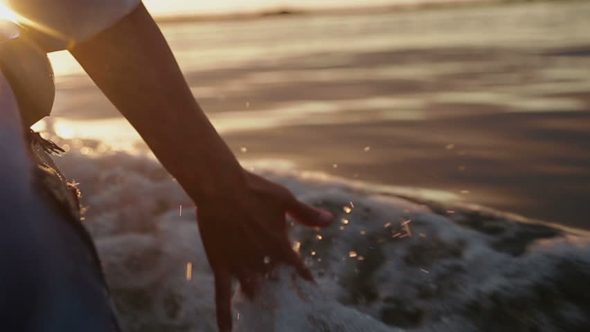 Hand glides over waves at sunset Royalty-Free Stock Footage #4780511