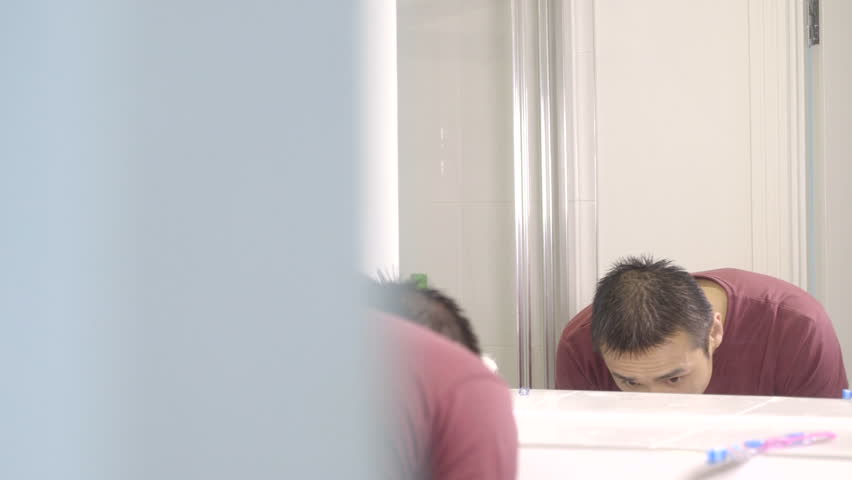 MS PAN Young man washing face in bathroom mirror