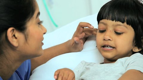 Close up of a young pediatric patient receiving treatment from a South Asian nurse in a children's hospital