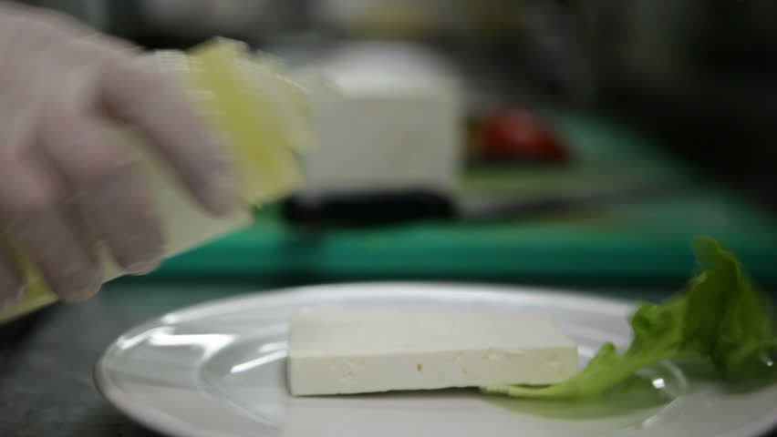 Cook pours olive oil on feta cheese