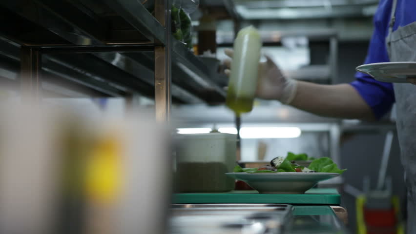 Chef pours olive oil on salad