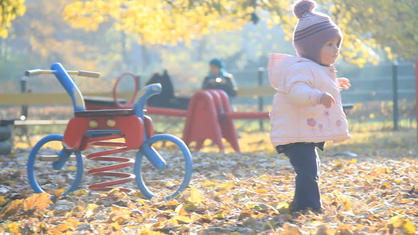 Small child plays on the playground in park in autumn 