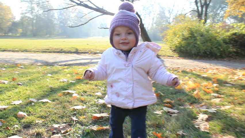 Cute baby learns to walk in a park