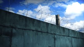 Barbed wire and concrete wall on a sunny day. This clip is loop ready.