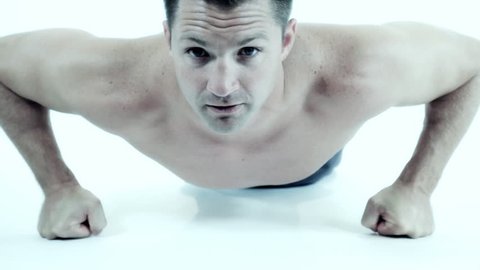 A young muscular man doing push-ups and looking at the camera. Blue tint