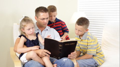A father reads to his children from the Holy Bible.