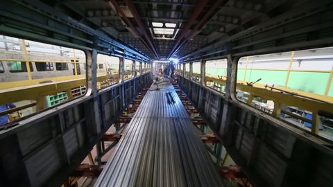 Workers weld inside dark train coach at workshop in factory