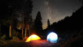 Time lapse star trail streaks over two lite tents in Big Meadow in Sequoia National Forest near Kernville, California.