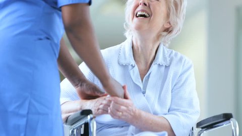 Close up of African American nursing professional reassuring elderly female patient recovering from treatment in wheelchair