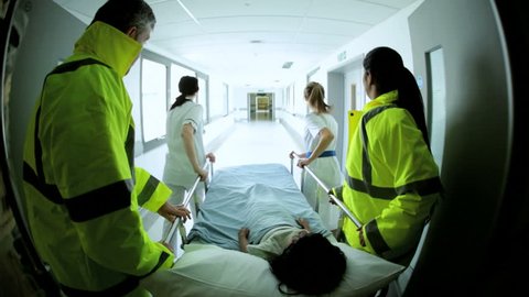 Wide angle view of paramedics rushing an injured child patient into a hospital for emergency critical treatment