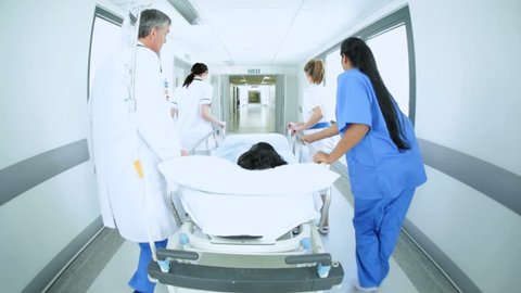 Wide angle view of multi-ethnic medical staff transferring child patient on hospital bed to emergency care center for treatment