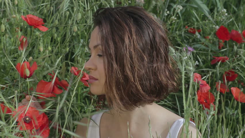 a beautiful young woman outdoors in the countryside surrounded  by flowers
