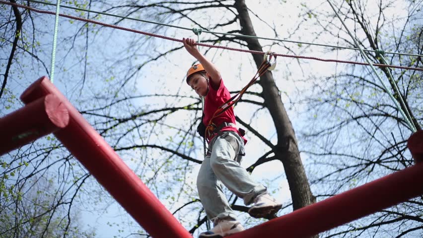 Young climber skilfully goes by pendant log bridge on high ropes course Royalty-Free Stock Footage #4813823