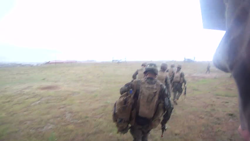Military combat mission solider running with automatic machine gun setting up to engage enemy in war. Marine running through desert and setting up gun to fire at enemy position.