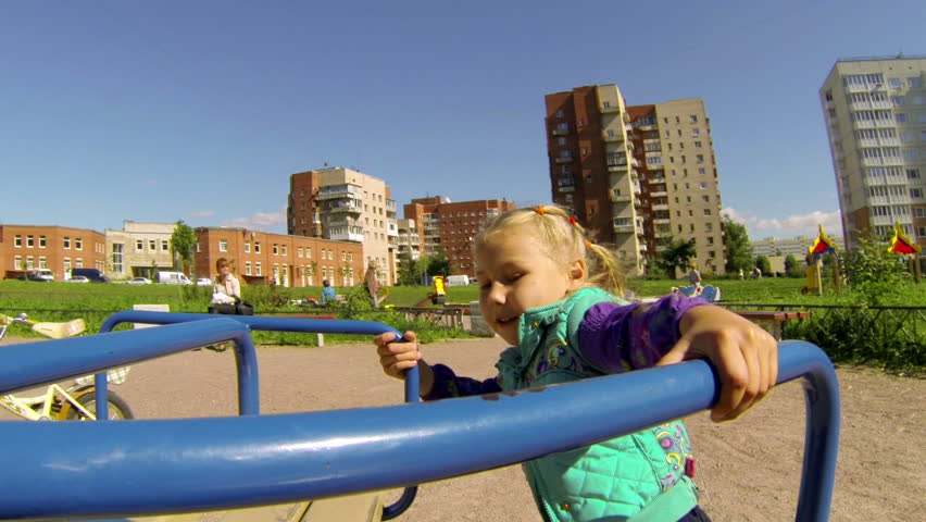 Child playing at playground, children spinning, rotating on a merry-go-round
