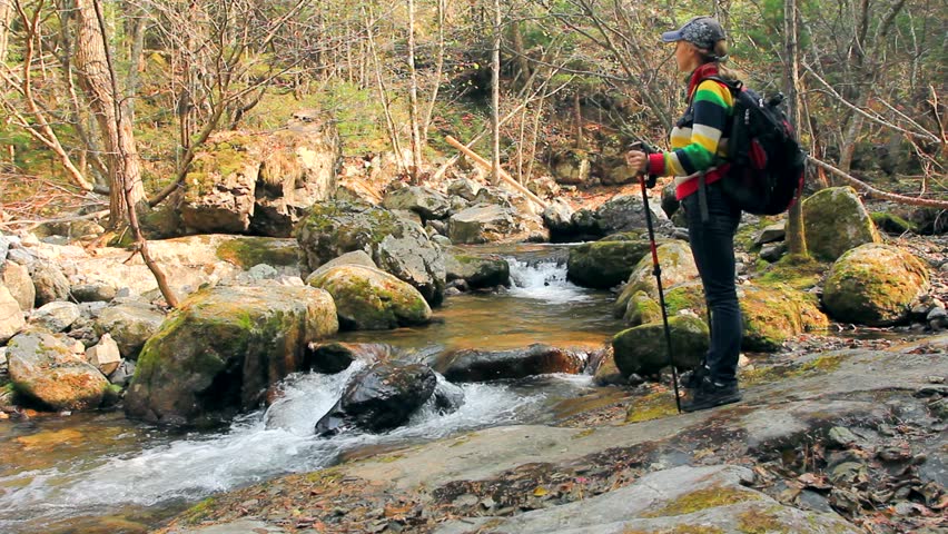 Lone young female reaches a stunning waterfall on her hiking adventure