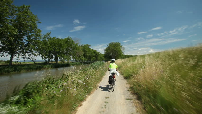 Slow motion - Retired couple cycling beside river on holiday