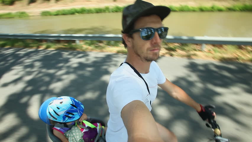 Slow motion - Man cycling with kid in bike seat