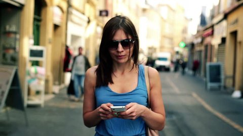 Pretty woman with smartphone walking in the city
