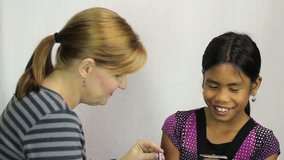A cute 11 year old Asian girl gets make up put on for the first time by her mother.