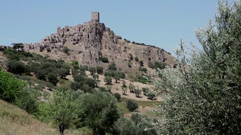 View of Craco, abandoned village due to landslide, with olive trees in the countryside of Basilicata, Italy. Italian travel in summer. Sequence, clip 2 of 2