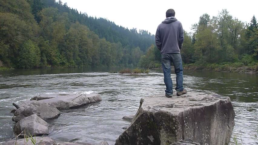 Model released man enjoying river view in Oregon wilderness.