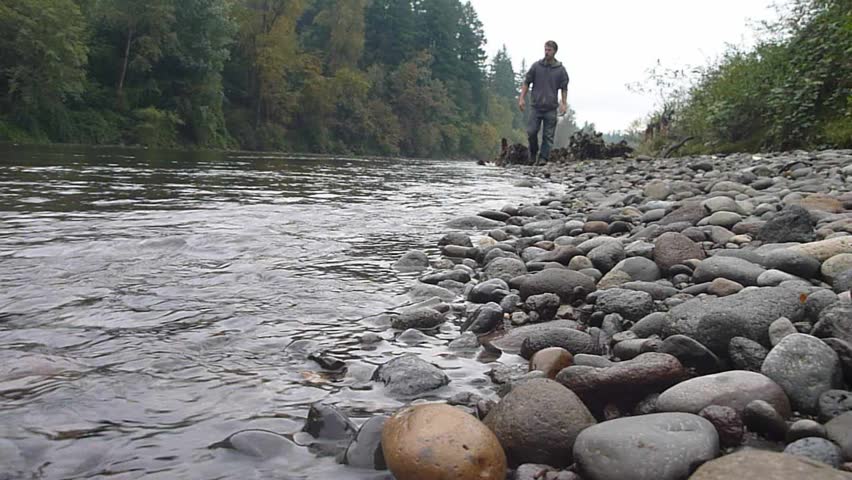 Model released man walking away on river rock in Oregon wilderness.