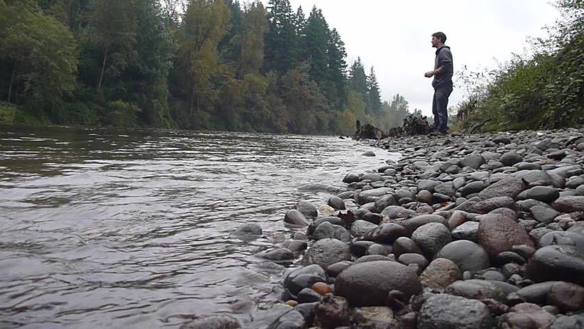 Model released man skipping stones at river in Oregon.