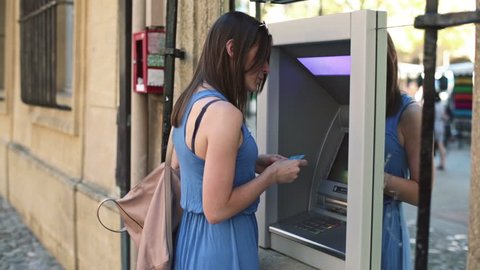 Young woman taking cash from ATM machine in the city
