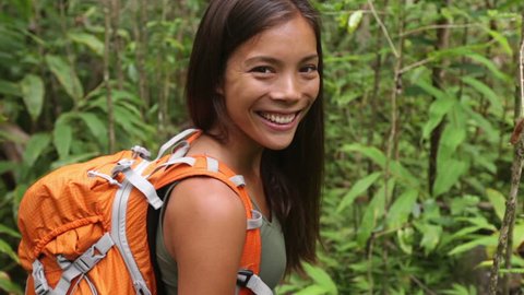 Hiking woman gesturing come along follow me, waving and hand looking at camera. Young female hiker walking with backpack in rain forest nature on Maui, Hawaii, USA. Mixed race Asian Caucasian girl.