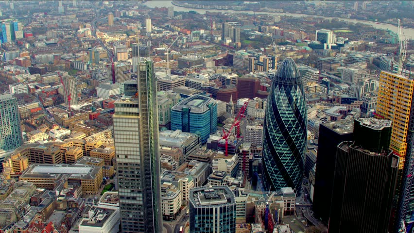 Dramatic aerial shot of the City of London financial district skyline. Features the Gherkin / 30 St Mary Axe building - shot then reveals Tower Bridge.