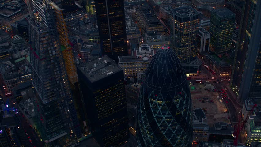 Dramatic evening aerial sequence of The City of London financial district, flying over the Gherkin building (30 St Mary Axe) and the Tower 42 building.