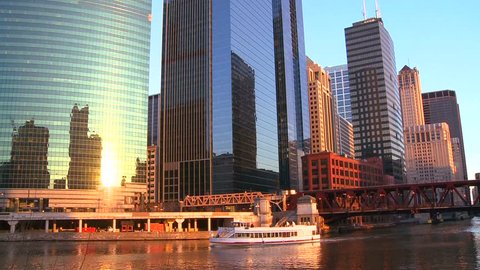 Boats travel on the Chicago River in front of the skyline.