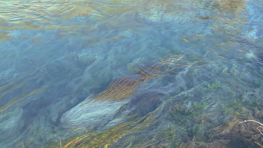 Blue water flows in a mountain stream in a beautiful abstract patterns.