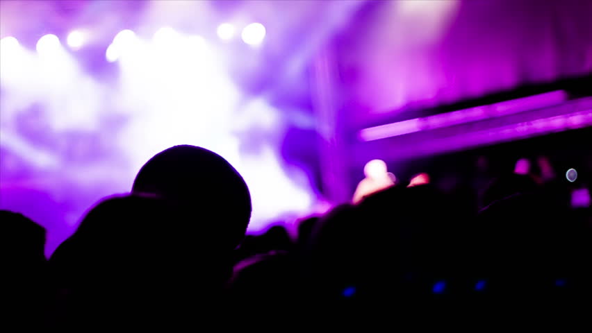 De-focused footage of young people dancing at rock festival concert