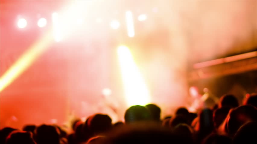 De-focused footage of young people dancing at rock festival concert