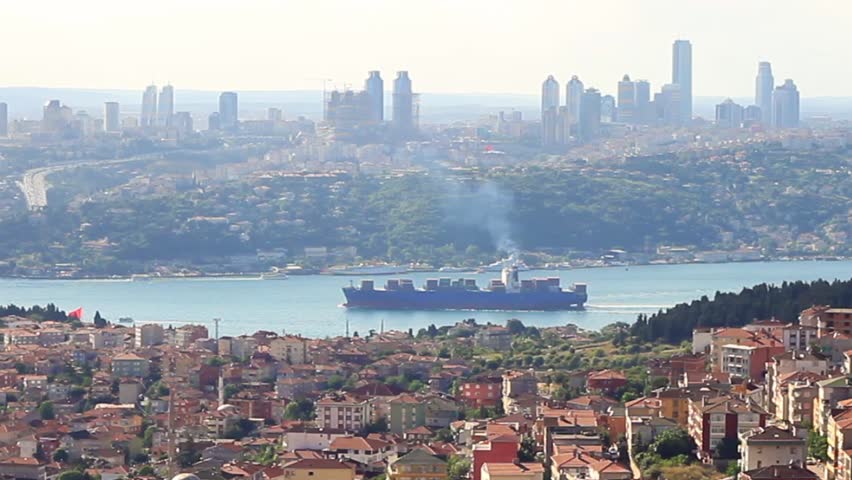 Istanbul in smog with a container ship passing in Bosporus. Zoom out, HD Video.