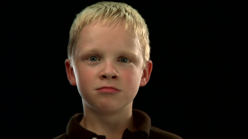 A young blond boy stares intensely into the camera on a black background