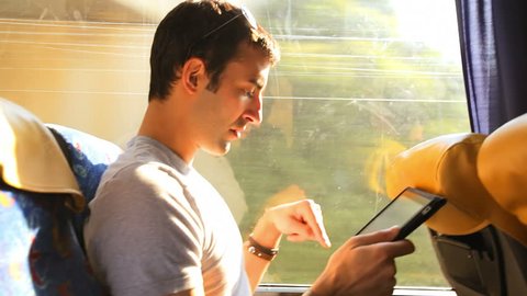 A young man looks through his tablet as he takes a bus ride
