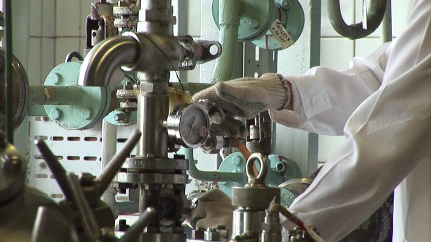 Worker turns the valve in the pipe