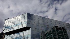 reflections of clouds moving in glass mirrored office tower