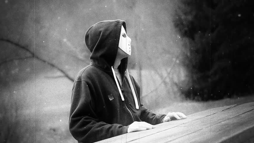 A retro stylized film look of a masked killer sitting in the forest.