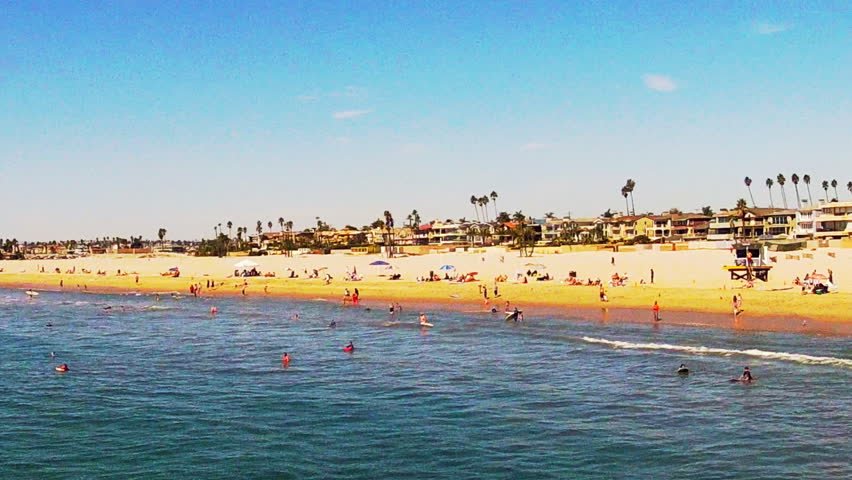 A wide shot of people swimming in the surf, people on the beach and beach homes
