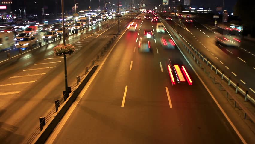 Highway through city at night time lapse. Busy light trail traffic on a freeway