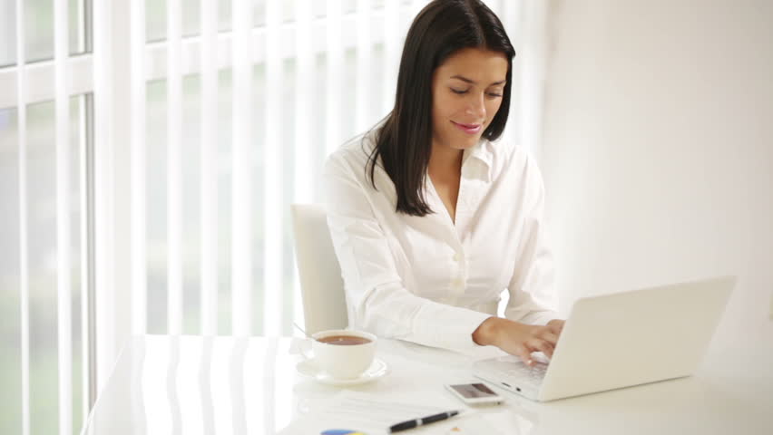 Cute young woman sitting at office desk using laptop closing it looking at