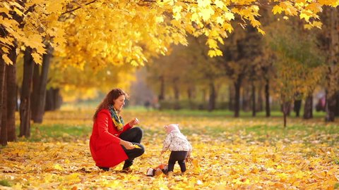 Mother and baby playing in a beautiful autumn park