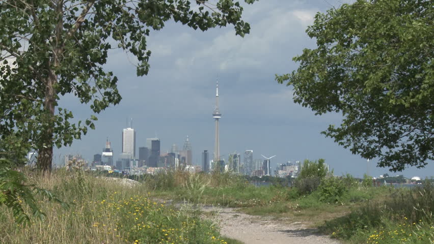 View of Toronto city skyline seen through trees in a park.