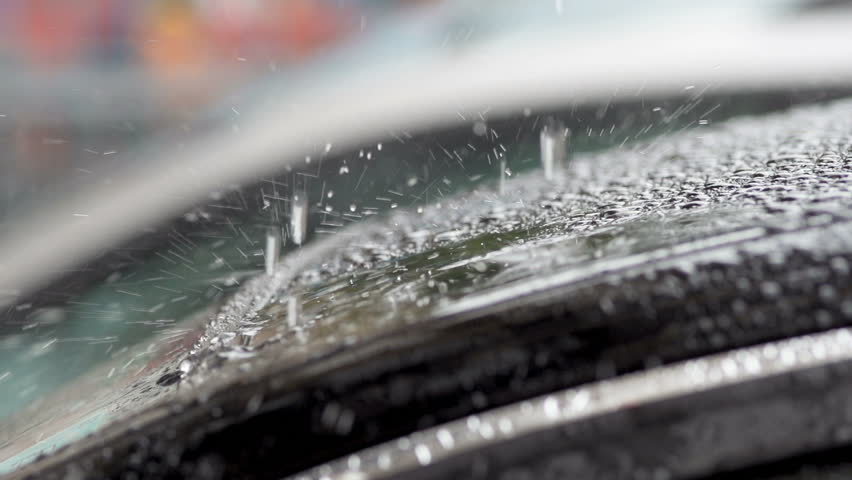 Close-Up Slow Motion Of Heavy Rain Drops Splashing Onto The Car On A Rainy Day.